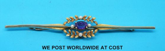 An Edwardian yellow metal brooch marked 15ct set with an amethyst and seed pearls