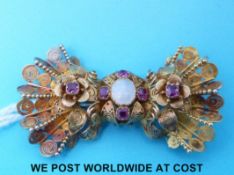 A filigree brooch set with rubies and an opal to the centre.