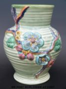 A Clarice Cliff Newport Pottery vase with moulded decoration of flowers and vines over ribbed green