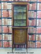 An Edwardian glazed bookcase cabinet over a bow fronted single inlaid door raised on tapering legs