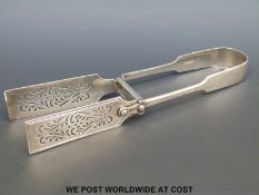 A pair of Victorian fiddle pattern asparagus servers with pierced decoration,