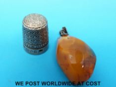 A hallmarked silver James Walker thimble and an amber pendant