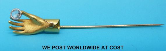 A yellow metal stick pin in the form of a hand set with a rose cut diamond