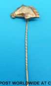 A yellow metal stick pin set in the form of a horse with a ruby eye.