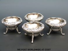 A set of four hallmarked silver Art Nouveau open salts raised on three feet,