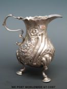 A Georgian hallmarked silver cream jug raised on three hoof feet, London 1807,