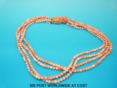 A four strand angel skin coral necklace with carved floral clasp, in original silk envelope,