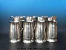 A collection of four stainless steel and four pewter style jugs