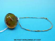 A bi-coloured 9ct gold bracelet and a silver ring set with pressed amber