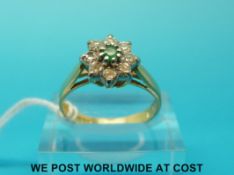 An 18ct gold ring set with a central emerald surrounded by diamonds (size O)