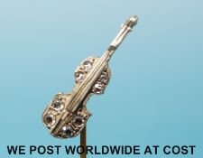 A yellow metal stick pin set with diamonds in the form of a cello
