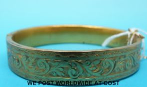 A 9ct gold bangle with chased floral decoration (18.