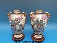 A pair of Japanese Satsuma vases, approximately 15cm tall, on wooden stands,