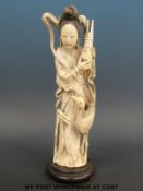A Japanese Meiji period okimono of a lady holding a pot containing bound bamboo with a large bird