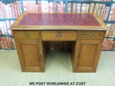 A leather inset pine twin pedestal desk with cupboards below three drawers (W119 x H79 x D60cm)