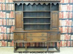 An oak dresser, the top having plate racks flanked by cupboards,