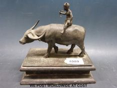 A bronze figure of a water buffalo with young boy astride,