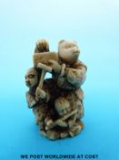 A Japanese Meiji period signed carved ivory netsuke of three masked figures in a theatrical scene
