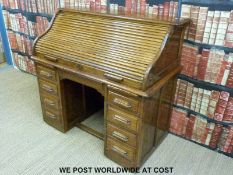 An oak roll top desk with fitted interior above a central drawer,