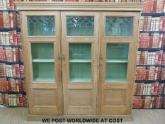 A pine housekeeper's or display cupboard with adjustable shelves behind the part-glazed doors (H197