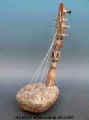 African tribal bow harp, the shaft carved with a figure and the base covered in animal hide,