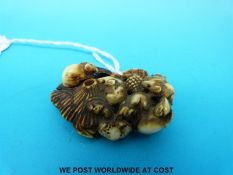 A Japanese Meiji period carved ivory netsuke of rabbits foraging for food on an upturned mushroom