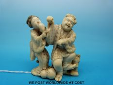 A signed Japanese Meiji period ivory okimono of a man and woman laughing,