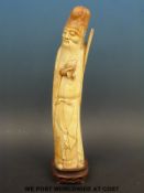 A 17th/18thC Chinese ivory figure of an elder holding fruit, probably pomegranate,