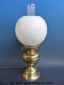 A brass oil lamp converted for modern electric use complete with glass shade
