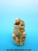 A Japanese Meiji period carved ivory netsuke of three children playing hide and seek around a large
