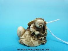 A signed Japanese Meiji period carved ivory netsuke of a crawling man with a child on his back (3.