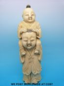 A Japanese Meiji period carved ivory okimono of a father carrying his son on his shoulders (13.