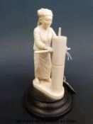 An early 20thC carved Indian ivory figure of an artisan grinding grain,