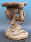 An African tribal stool with a kneeling female figure supporting the seat on her head (33cm tall)