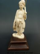 An early 20thC carved Indian ivory figure of a man in native clothes, holding a duck,