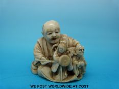 A signed Japanese Meiji period carved ivory netsuke of an artisan painting figures,