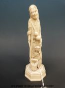 A Japanese Meiji period carved ivory okimono of a flower seller with a stick,