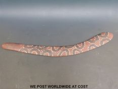 An Aboriginal wooden boomerang with painted decoration of dark loops surrounded by white spots on