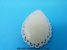 A jadeite pedant in a pear shape carved with lily pads to one side and a young boy to the other