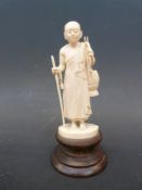 An early 20thC carved Indian ivory figure of a Buddhist monk holding a stick,