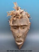 An African tribal mask with feathers and nails to the top,