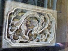 A carved Chinese hardwood panel depicting a dragon in a glazed box frame and a Chinese tapestry of