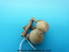 A signed Japanese Meiji period carved ivory netsuke in the form of two pomegranates and a leaf