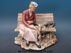 A Capodimonte figure of a lady sitting on a bench with two dogs