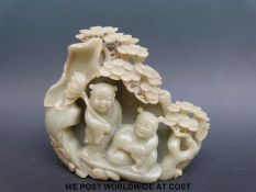A Chinese carved jadeite figural group depicting children and prunus to one side and lily pads to