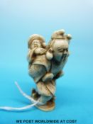 A Japanese Meiji period carved ivory netsuke of a bearded man carrying a child (5.
