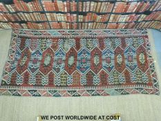 A Turkoman rug decorated with fourteen joined guls surrounded by geometric borders (275 x 125cm)