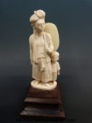 An early 20th carved Indian ivory figure of a man and child both in native clothing,
