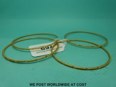 Four Middle Eastern yellow metal bangles with ridged and cross decoration (30.