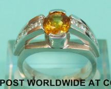 A white metal ring marked 14K 2346 set with a central orange stone, possibly a sapphire,